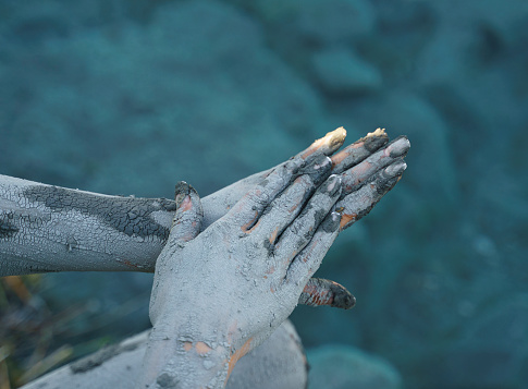Woman applying mineral-rich mud mask to her hands in the lake of Dalaman, Mugla, Turkiye