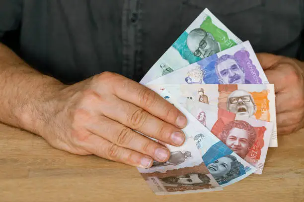 Colombia currency, a man holds a fan of money in his hand, Business and financial concept