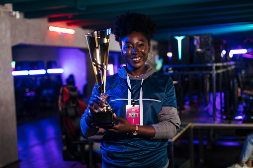 A female professional gamer holds a trophy after winning an esports tournament