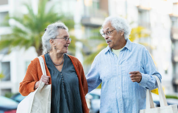 istock Senior couple walking outdoors carrying reusable bags 1412902441