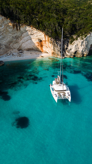 Amazing coast with beautiful beach and forest around on Ionian sea and anchored catamaran in bay. Kefalonia island, Fteri beach, Greece