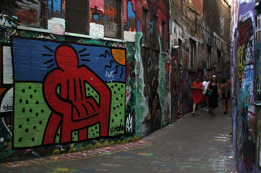 Young female street artist draws graffiti using colorful sprays