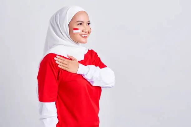 Happy young Asian muslim woman in red white t-shirt greeting to celebrating indonesian independence day on 17 august isolated on white background