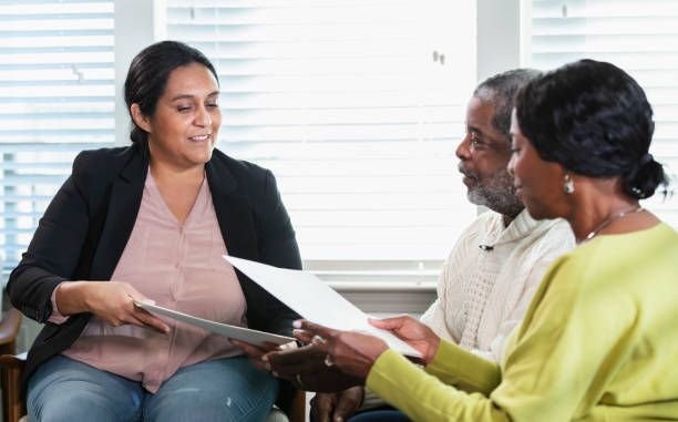 Senior African-American couple with in home consultant A senior African-American couple meeting with an in-home consultant. The mature Hispanic woman could be a Real Estate Agent, a financial advisor, or insurance agent. They are sitting in the living room conversing, reviewing paperwork. florida real estate house home interior stock pictures, royalty-free photos & images