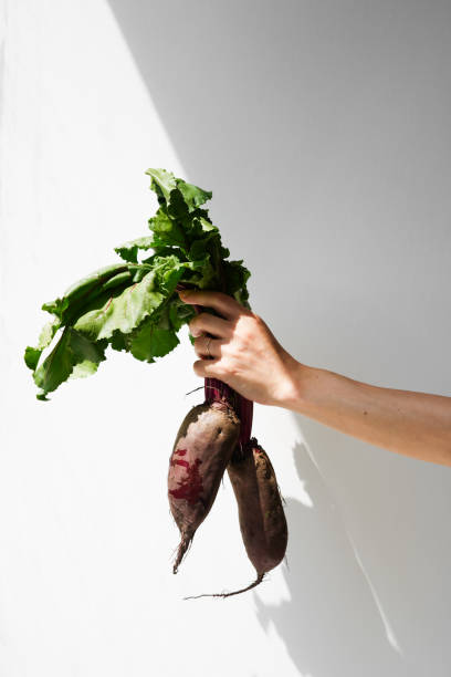 istock Fresh raw beets with stem in hand on light background with shadows 1412907677