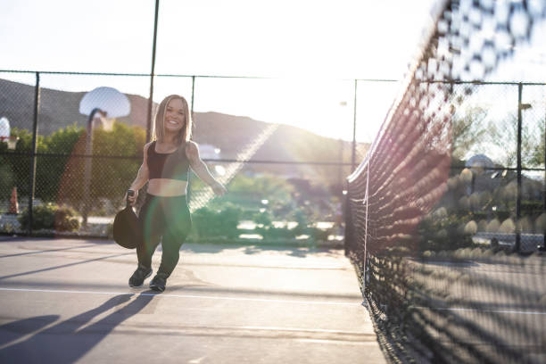 A beautiful woman with dwarfism playing pickle ball at the park and having fun.