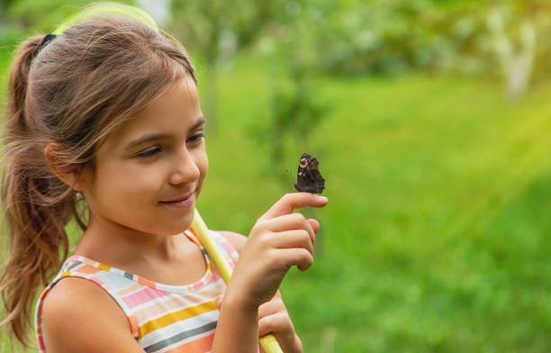 istock Cute Girl Looking At Butterfly On Finger 1412915369