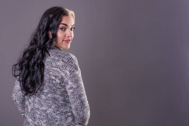 Rear view of woman looking at camera. Studio Shot.