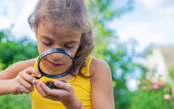 istock Girl Looking At Soil Through Magnifying Glass 1412918281