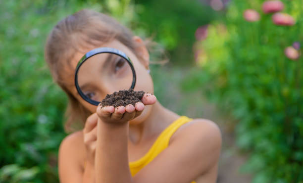 istock Girl Looking At Soil Through Magnifying Glass 1412918282