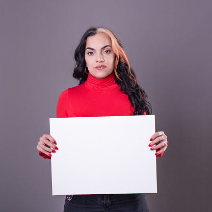 Beautiful woman holding a blank sign against a grey background