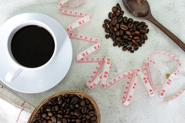 Cup of coffee and coffee beans background with measure tap on white desk. stock photo