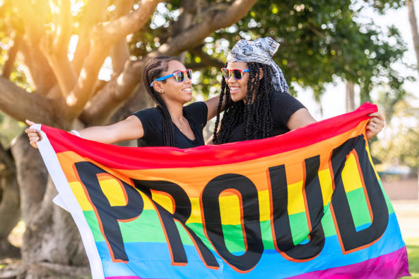 Afro-latinx young lesbians holding a rainbow banner with the word Proud written on it Afro-latinx young lesbians holding a rainbow banner with the word Proud written on it afro latinx ethnicity stock pictures, royalty-free photos & images
