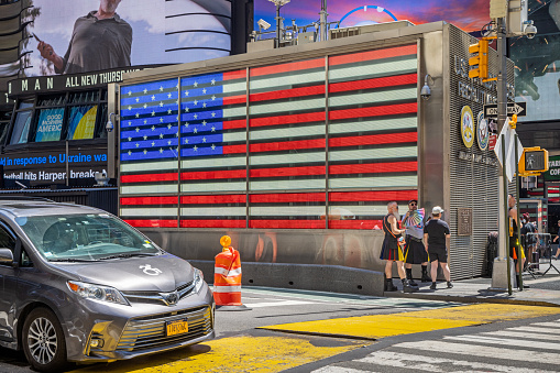Times Square, New York, NY, USA - June 26, 2022: The famous American flag sign and a couple of men in kilts