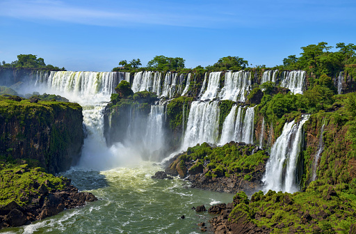Scenic view of the breathtaking Iguazu Falls crashing onto rocks in the rainforest on a sunny day