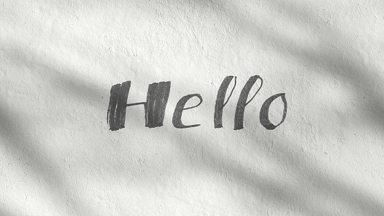 Hello handwriting text written on a white concrete wall on a sunny day. Greeting message and welcome quote. Abstract shadow of trees. Modern design.