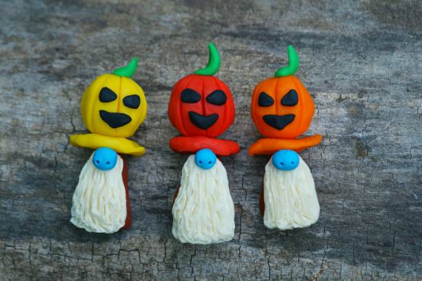 istock Figures of three dwarfs decorated with a pumpkin on a background of tree bark. 1412927069