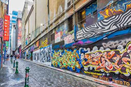 Pedestrians walk past a row of street art on the famous Hosier Lane in downtown Melbourne, Victoria, Australia on an overcast day.