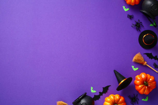istock Happy Halloween holiday concept. Flat lay composition with Halloween decorations, pumpkins, bats, spiders, witch hats and brooms on purple background. Top view, overhead. Halloween greeting card 1412930165