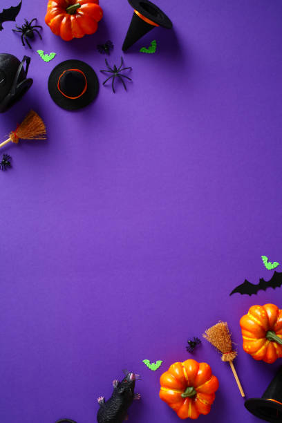 istock Happy Halloween holiday concept. Vertical banner design with Halloween decorations, bats, pumpkins, spiders, witch hats and brooms on purple background. Flat lay, top view, copy space. 1412930189
