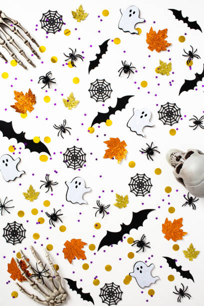 istock Happy Halloween holiday concept. Pattern made of Halloween decorations, bats, skeleton hands, ghosts, spiders, webs on white background. Flat lay, top view. 1412930278