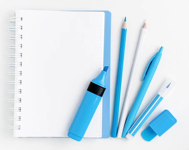 istock White blank notebook and blue markers with pencils and pen on white background. Flat lay, mockup. 1412930382