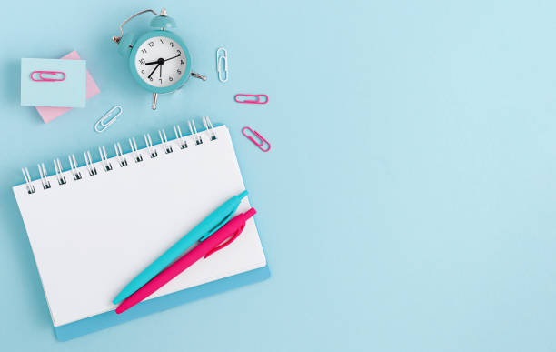 istock Template mockup. Workspace with notebook, clock and pens on pastel blue background. Top view. Copy space 1412930992