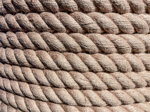 texture, background. a strong, solid rope is wound on a reel. twine for binding made of durable brown material. threads are pulled from the rope.
