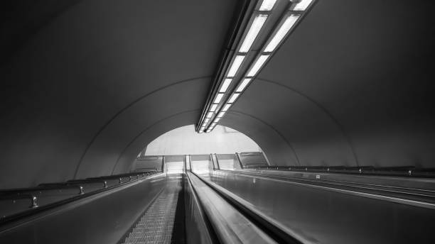 istock Black and white subway escalators in deep perspective 1412931559