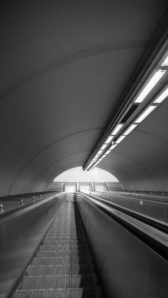 istock Black and white subway escalators in deep perspective 1412931577