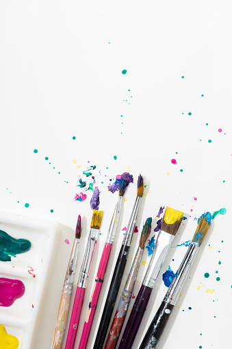 Art Paint brushes with colorful splatter on white canvas paper. Copy space