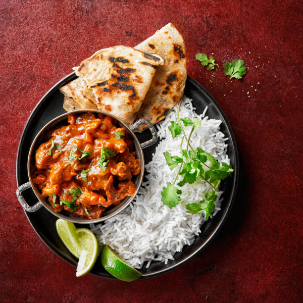 pollo tikka masala picante carne de curry alimento mantequilla de pollo, arroz y pan naan sobre fondo oscuro de vid roja. plato tradicional indio. - tomatoes on vine fotografías e imágenes de stock