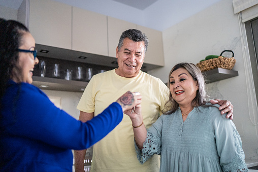 Real estate agent giving keys to mature couple at home