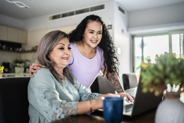 istock Senior woman working at home using laptop - with her daughter 1412934137