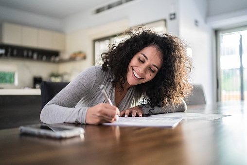 Mid adult woman filling document at home