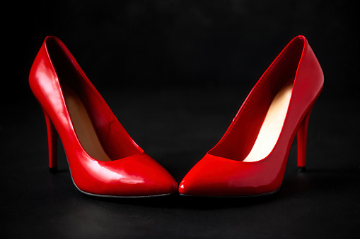 bright red high-heeled shoes stand on a dark background