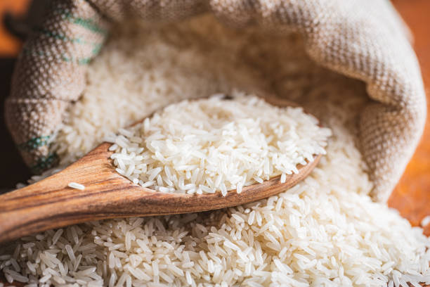 Uncooked white rice on wooden spoon. Uncooked white rice on a wooden spoon. rice sack stock pictures, royalty-free photos & images