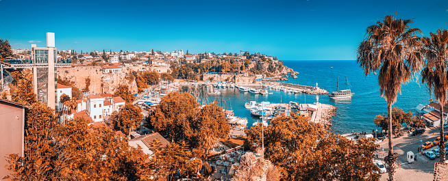 tourist cruise ship or yacht is sailing to Antalya old town harbor from open sea. Trip and excursion and vacation in Turkey background