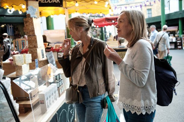 due amiche anziane che si godono lo shopping di formaggio in un mercato di strada. - senior adult aging process supermarket shopping foto e immagini stock