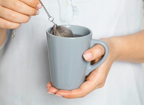 A woman brews tea with strainer.