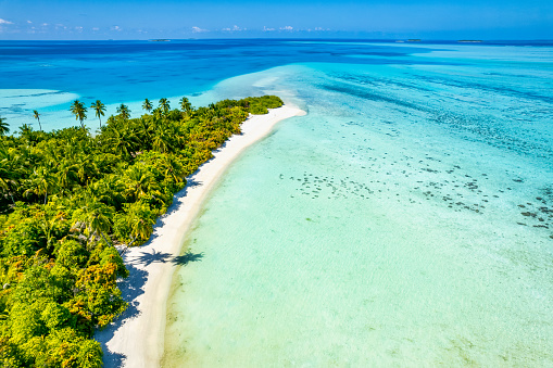 Aerial drone view of desert island and coral reef in Maldives