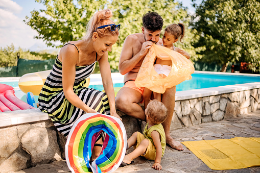 Happy family with two children at the pool, inflating swimming tires