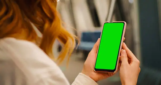 Photo of Over the sholder shot of woman watching green screen phone on the underground.