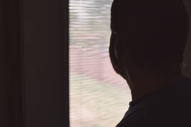 istock Depressed Man Looking Out the Window 1412956719