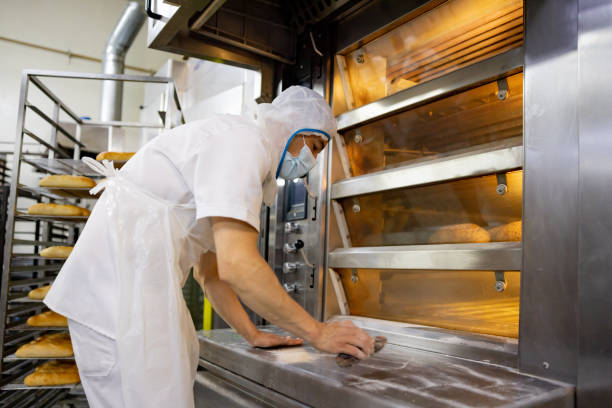 istock Baker working at an industrial bakery and cleaning the oven 1412956724