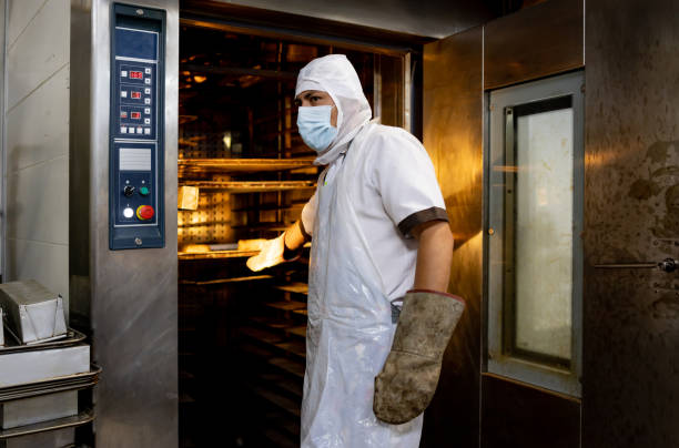 istock Baker taking the bread out of the oven at the bakery 1412956766
