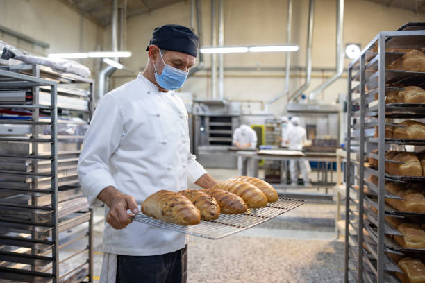 istock Baker carrying a tray of freshly baked bread 1412956785
