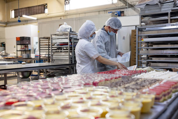 ingenieur, der in einem lebensmittelverarbeitungsbetrieb arbeitet und qualitätskontrollen an einigen desserts durchführt - nahrungsmittelfabrik stock-fotos und bilder