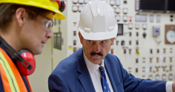 istock Shot of Power Plant Executive Looking at Engineer 1412964831
