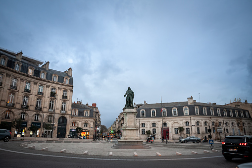 Picture of  the Louis de Tourny statue in front of a heavy traffic of cars and bicicyles in the city center of Bordeaux, France.